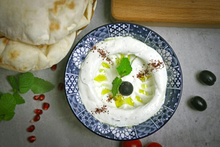 Delicious creamy labneh topped with olive, mint, and olive oil, served with flatbread.